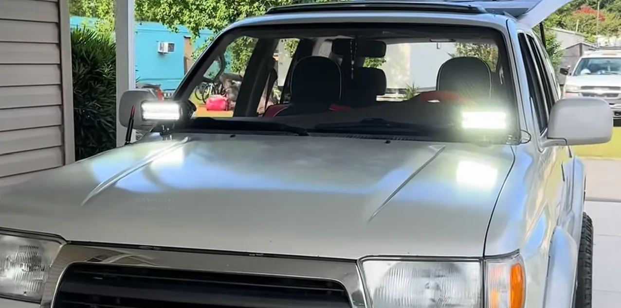 Silver Toyota 4Runner with a pair of bright LED auxiliary lights mounted on the cowl at the base of the windshield, demonstrating one of the best placement options discussed in the guide.