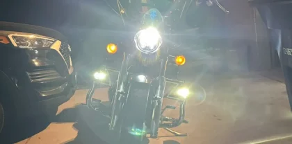 Front view of a motorcycle with illuminated auxiliary lights mounted on crash bars at night, showcasing how to install auxiliary lights on motorcycle for nighttime riding.